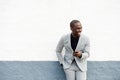 Happy African American business man leaning against wall with cellphone Royalty Free Stock Photo