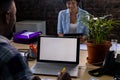 Happy african american business people sitting at desks, using tablet and laptop with copy space Royalty Free Stock Photo