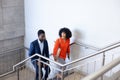 Happy african american business people walking and talking on stairs