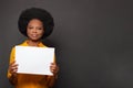 Happy African American business woman holding sign or white empty paper banner isolated on black background Royalty Free Stock Photo