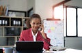 Happy african-american business woman talking on mobile at office. Young female manager consulting on phone, using Royalty Free Stock Photo