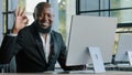 Happy african american businessman adult worker typing on laptop working remotely turn to camera smiling make approval Royalty Free Stock Photo