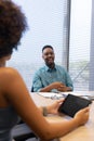 Happy african american businessman planning strategy with hispanic businesswoman in boardroom Royalty Free Stock Photo