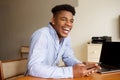 Happy african american businessman sitting at computer table with mobile phone Royalty Free Stock Photo