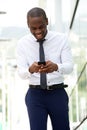 Happy african american businessman walking and looking at cellphone on city street Royalty Free Stock Photo