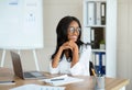 Happy African American businesswoman having break from online work, daydreaming near laptop at office