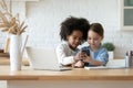 Happy African American and Caucasian little girls using phone together Royalty Free Stock Photo