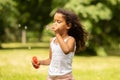 happy african american child in park, a girl plays in nature in the summer, a kid blows soap bubbles Royalty Free Stock Photo