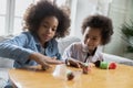 Happy african american children involved in creating figures with plasticine.