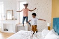 Happy african american children jumping at bedroom. Royalty Free Stock Photo