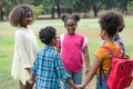 Group of African American children plays a game holding hands together in a circle in the park Royalty Free Stock Photo