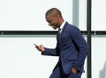 Happy african american corporate businessman walking with cellphone in city Royalty Free Stock Photo