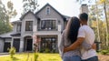 Happy african american couple embracing in front of their new big modern house, rear view. Buying your dream home Royalty Free Stock Photo