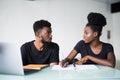 Happy African American couple of enterpreneurs develop new business strategy on portable laptop computer, use mobile phones for