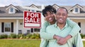 Happy African American Couple In Front of Beautiful House and For Sale Real Estate Sign. Royalty Free Stock Photo