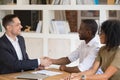 Excited black couple meeting handshake real estate agent in office