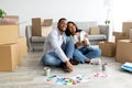 Happy african american couple planning renovation and dreaming, choosing color palettes together, sitting in new house Royalty Free Stock Photo