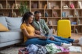 Happy african american couple planning vacation travel with laptop, reading tourist blog online, sitting near suitcases Royalty Free Stock Photo