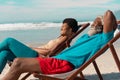 Happy african american couple relaxing on deckchairs against sea and cloudy sky on sunny day Royalty Free Stock Photo