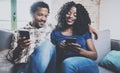 Happy african american couple relaxing together on the sofa.Young black man and his girlfriend using smartphones while Royalty Free Stock Photo