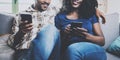 Happy african american couple relaxing together on the sofa.Young black man and his girlfriend using smartphones while Royalty Free Stock Photo