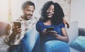 Happy african american couple relaxing together on the sofa.Young black man and his girlfriend using smartphones while Royalty Free Stock Photo