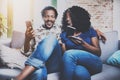 Happy african american couple relaxing together on the sofa.Young black man and his girlfriend using smartphones while Royalty Free Stock Photo