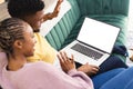 Happy african american couple sitting on sofa and using laptop with copy space in living room Royalty Free Stock Photo