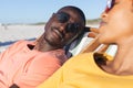 Happy african american couple in sunglasses sitting in deckchairs relaxing on sunny beach Royalty Free Stock Photo