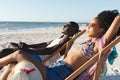 Happy african american couple in sunglasses sitting in deckchairs relaxing on sunny beach by the sea Royalty Free Stock Photo