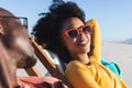 Happy african american couple in sunglasses sitting in deckchairs smiling on sunny beach Royalty Free Stock Photo
