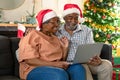 Happy african american couple wearing santa hats using laptop, having video call at christmas time Royalty Free Stock Photo