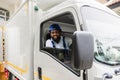 Happy African American delivery service man driver in uniform sitting smiling and looking on camera cheerful in a courier truck Royalty Free Stock Photo