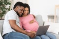 Happy african american expecting family using laptop at living room Royalty Free Stock Photo