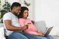 Happy african american expecting family using laptop, shopping online Royalty Free Stock Photo