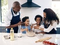 Happy african american family baking in their kitchen together. Cheerful mother and father playing with their sons while Royalty Free Stock Photo