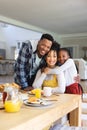 Happy african american family embracing at table at breakfast in morning at home, copy space