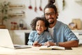 Happy african american family father and son sitting at table with laptop during distance education Royalty Free Stock Photo