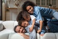 Happy African American family having fun, lying on cozy sofa Royalty Free Stock Photo