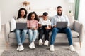 Happy african american family holding and using personal gadgets Royalty Free Stock Photo