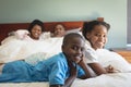 Happy African American family looking at camera while relaxing on bed in bedroom Royalty Free Stock Photo