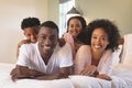 Happy African American family lying on bed and looking at camera Royalty Free Stock Photo