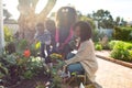 Happy african american family planting flowers and watering plants together