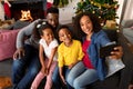 Happy african american family sitting on sofa and taking selfie, christmas decorations in background Royalty Free Stock Photo