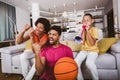 African American family of three watching tv and cheering basketball games on sofa at home