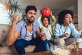 African American family of three watching tv and cheering sport games on sofa at home