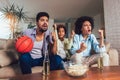African American family of three watching tv and cheering sport games on sofa at home