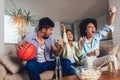 African American family of three watching tv and cheering sport games on sofa at home
