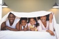 Happy African American family under blanket and looking at camera Royalty Free Stock Photo