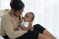 Happy African American family, young mother holding cute newborn baby girl in Arms with care smiling and sitting on bed at bedroom Royalty Free Stock Photo